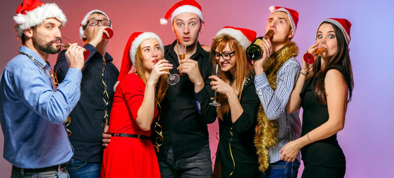 Fröhliche Menschen mit Weihnachtsmützen feiern ausgelassen – eine Erinnerung daran, dass Stress oft auch durch zu viele Termine entsteht.