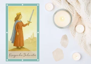 Tarotkarte Königin der Schwerter. Eine Frau mit Krone und Schwert steht auf einem Hügel vor einer kleinen Stadt. Sie verkörpert Klarheit, Selbstachtung und die Stärke, Grenzen zu ziehen und sich von belastenden Einflüssen zu lösen.