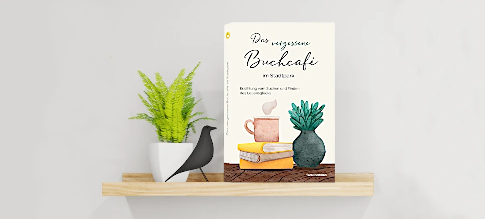 Buch „Das vergessene Buchcafé im Stadtpark“ auf einem beigen Holzregal vor heller Wand mit Dekoration.